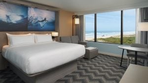 hotel room with bed, couch, working area and view of ocean beach